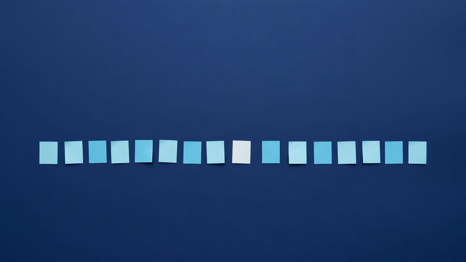 A row of small pale blue paper rectangles of varying height, all flat-topped, across a deep navy ground